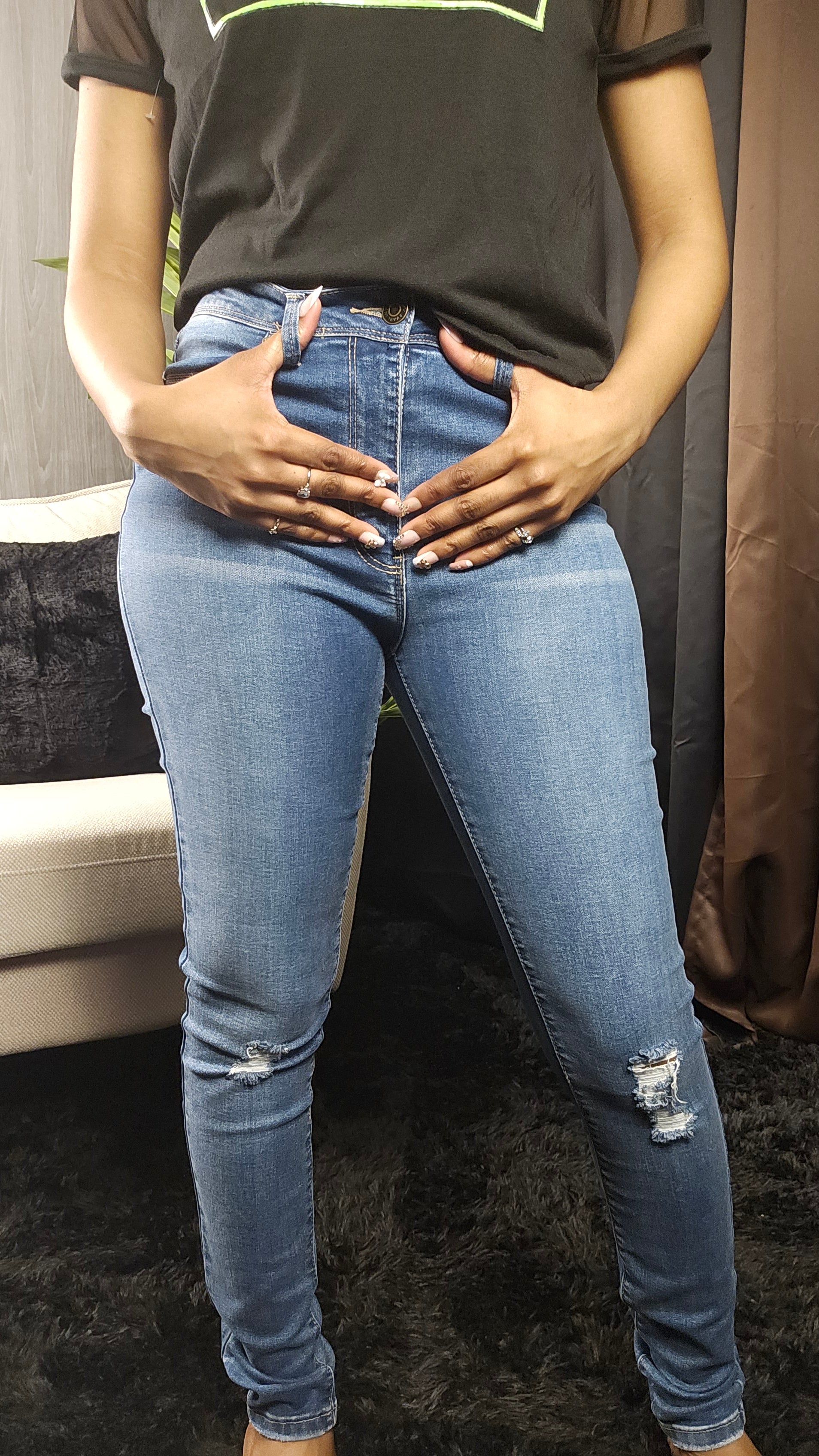 Person wearing blue jeans and a black shirt sitting on a couch.