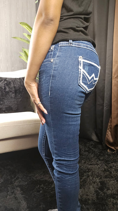 Person wearing blue jeans with a visible tear on the knee, standing indoors.