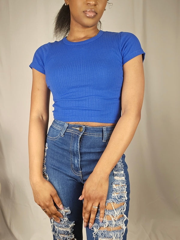 Person wearing a blue top and denim shorts on a beige background