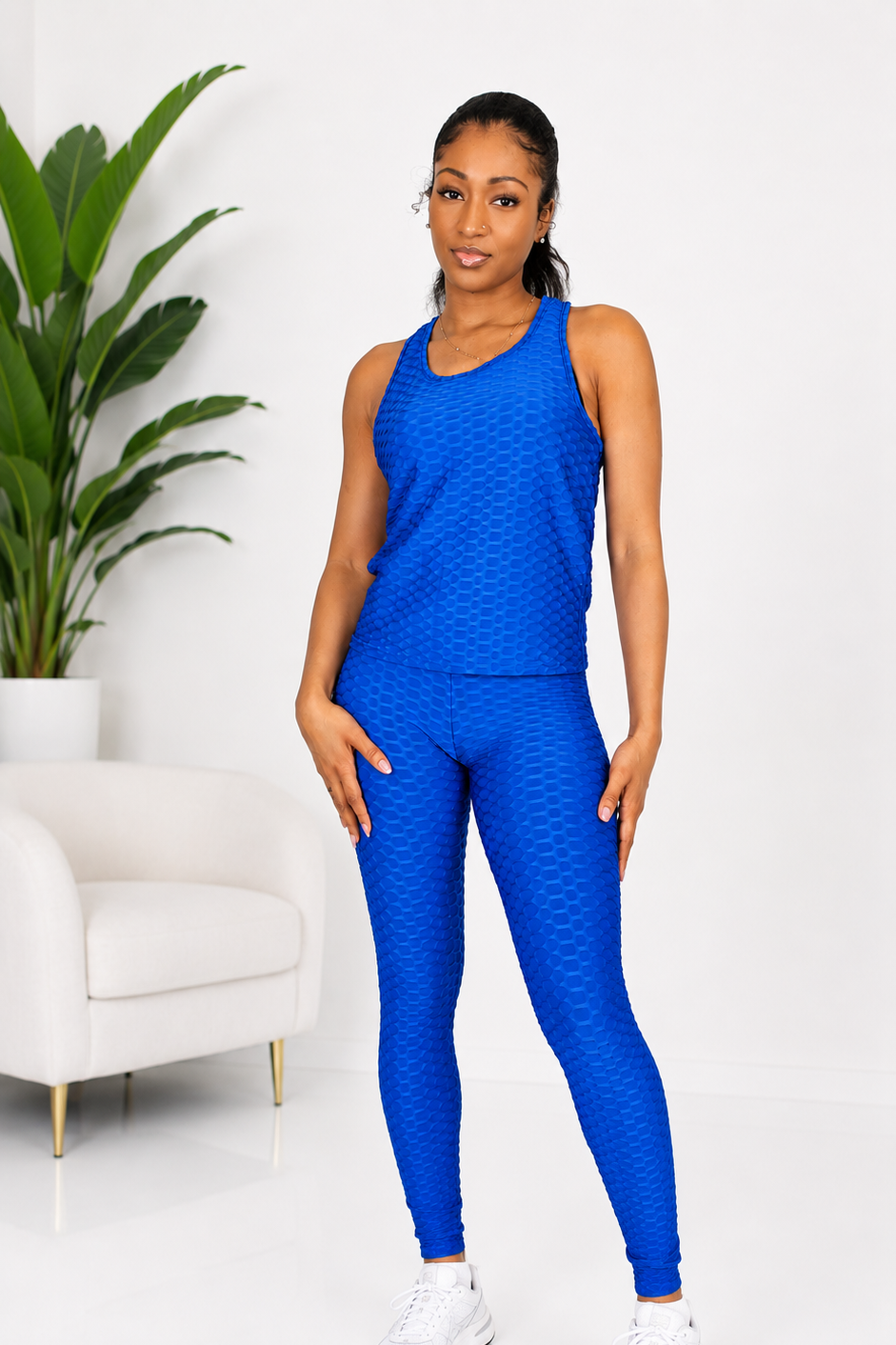 Woman wearing a blue athletic outfit in a minimalistic room with a plant.