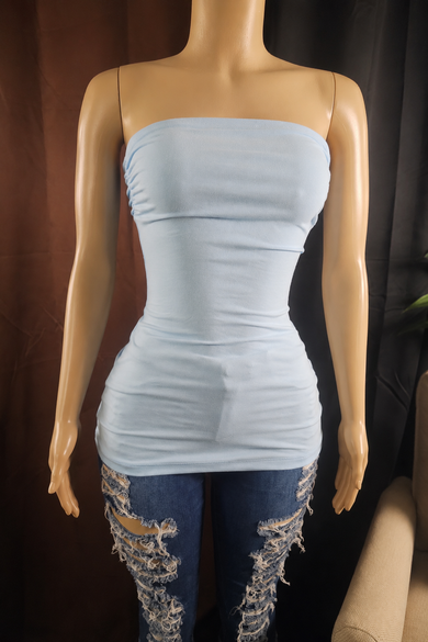 A light blue strapless tube top displayed on a beige mannequin torso, paired with distressed blue jeans against a dark brown and black backdrop.