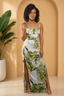 Woman in a floral dress standing in a room with a plant and archway.