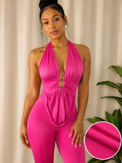 A woman modeling a bright hot pink halter-neck bodysuit with a deep plunging V-neckline, a central keyhole cutout, and a gathered waist. The image features a circular inset in the bottom right corner showing a close-up of the solid pink fabric texture.