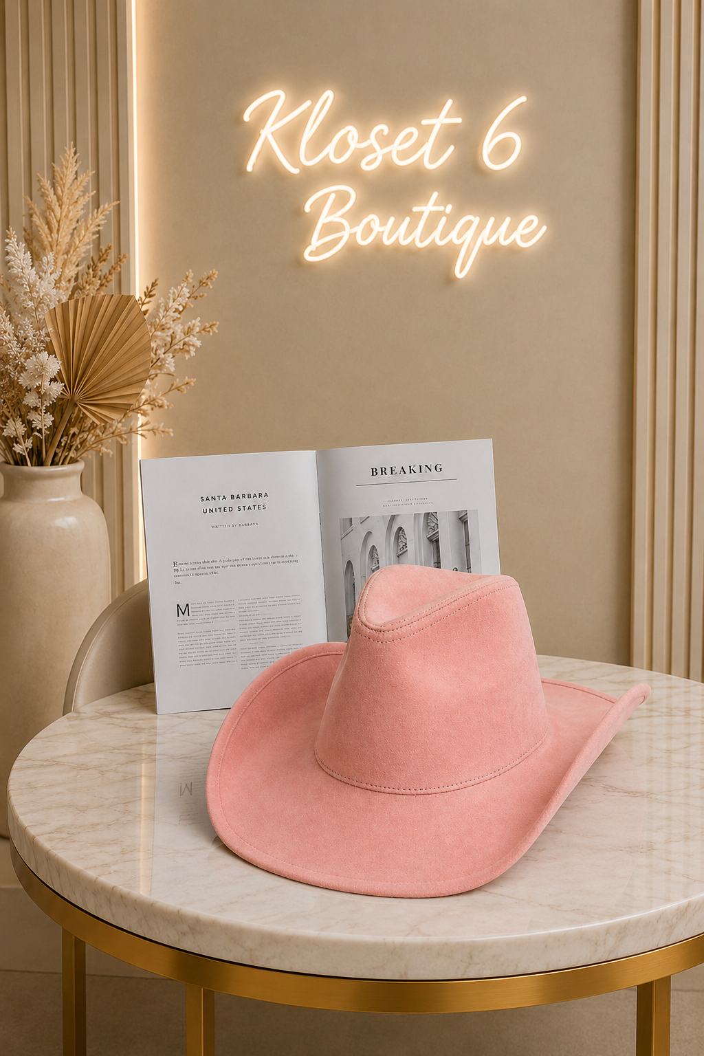 Pink hat on a marble table with a magazine and 'Kloset 6 Boutique' neon sign in the background.