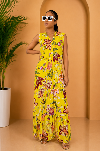 Woman in a yellow floral dress standing in front of an archway with a plant to the side.